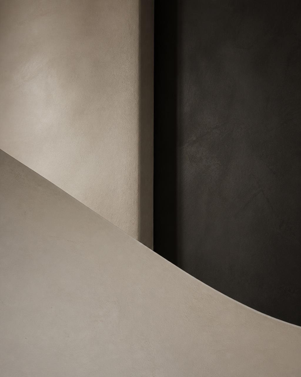 Abstract architectural composition of a curved ivory wall against a dark panel